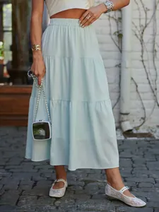 Woman in a light blue tiered long skirt standing outdoors