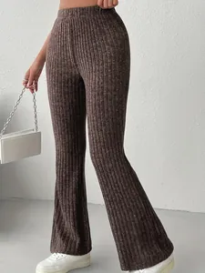 Dettaglio dei pantaloni svasati a costine marroni a vita alta in maglia testurizzata