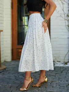 Side view of a white polka dot tiered maxi skirt with gold heels on an outdoor patio