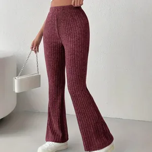 Dettaglio ravvicinato degli eleganti pantaloni a zampa a coste bordeaux a vita alta