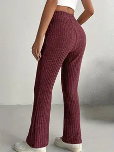 Vista posteriore dettagliata di pantaloni svasati a costine bordeaux a vita alta su una modella