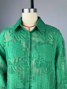 Detailweergave van een groen getextureerd shirt met lange mouwen en knopen op een mannequin
