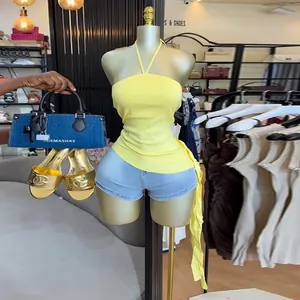 Modisches gelbes Neckholder-Top mit asymmetrischem Saum und Jeans-Shorts-Kombination