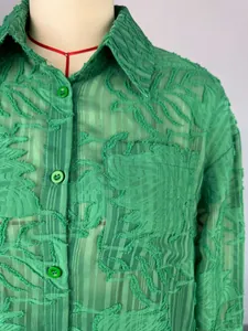 Detail van een groen overhemd met lange mouwen, getextureerde bladpatronen en knopen