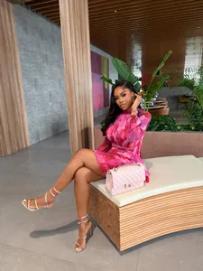 Elegant pink floral pleated A-line mini dress for summer, styled in a modern indoor setting