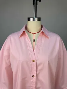 Detailansicht eines rosa lockeren Revershemdes mit braunen Knöpfen auf einer Schaufensterpuppe.