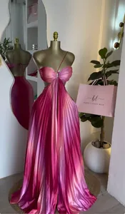 Elegante vestido largo plisado degradado rosa con cuello halter y corte en un maniquí