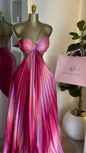 Primer plano de un dulce vestido largo plisado rosa degradado sobre un maniquí dorado