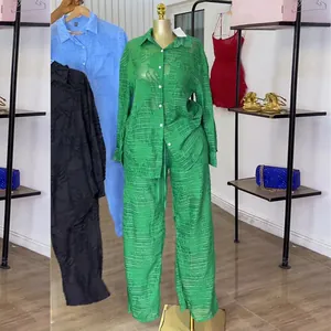 Detail van een groene tweedelige set voor dames met getextureerd shirt en wijde broek