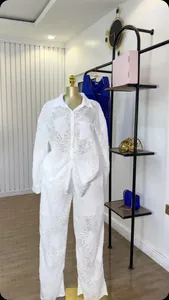 Witte tweedelige set met overhemd en broek van devoré-stof met bloemen op een paspop