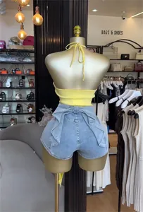 Rückansicht eines gelben Neckholder-Tops mit gerüschten Jeansshorts auf Mannequin.