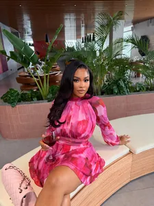 Elegant pink floral printed pleated A-line mini dress worn in a stylish lounge setting