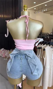 Rückansicht eines rosa Neckholder-Tops mit Jeansshorts und großer dekorativer Schleife