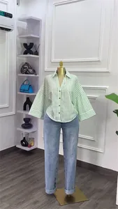Gesamtansicht eines grün-weiß gestreiften Hemdes mit Jeans an einer Schaufensterpuppe.