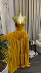 Detailed view of an elegant yellow pleated maxi dress displayed on a gold mannequin.