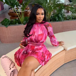 Elegant pink floral print pleated mini dress with cinched waist shown in a lifestyle setting