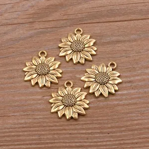 Gros plan de quatre breloques tournesol dorées pour bijoux DIY sur bois.