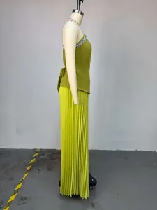 Seitenprofildetail des limettengrünen Sets mit Strass-Oberteil und Plisseehose am Mannequin.