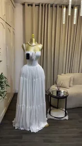 Elegant white spaghetti strap maxi dress with pleated tiered skirt shown on a gold mannequin