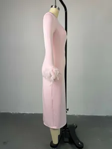 Seitenansicht eines rosa langärmeligen Midikleids mit eleganten Federbündchen auf einer Puppe.