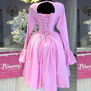 Detail of pink elegant dress featuring a unique lace-up back design and flared sleeves.