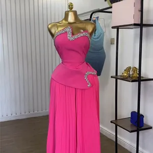 Detail des pinkfarbenen trägerlosen Oberteils mit Strasssteinen und Plissee-Hose
