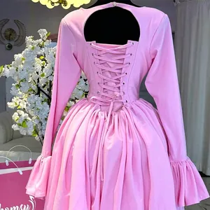Back detail of elegant pink long-sleeved dress with lace-up corset and ruffle cuffs