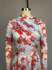 Detalle de top de manga larga con drapeado y falda plisada con estampado de coral.