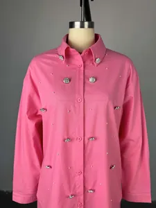 Primer plano de camisa rosa de manga larga con cuentas de perlas y botones de flores