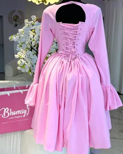 Back detail of pink long-sleeved dress with elegant corset lace-up and stylish ruffles.