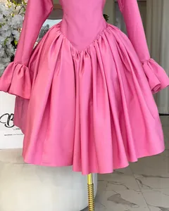 Close-up of elegant pink dress featuring ruffled cuffs and gathered pleated waist detail.