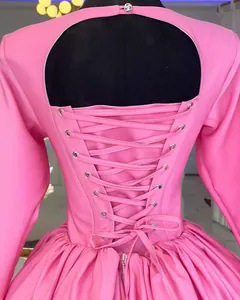 Detailed view of an elegant pink long sleeve dress with a stylish lace-up back.