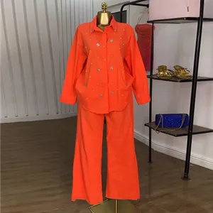Conjunto de dos piezas naranja vibrante con camisa de cuentas y pantalón de pernera ancha.