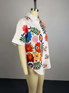 Vista laterale dettagliata di una camicia bianca a maniche corte con ricamo floreale su manichino