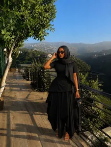 Elegant black irregular maxi dress with matching hijab worn in outdoor scenic setting