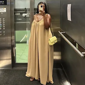 Mujer con vestido largo caqui suelto con escote en V en un selfie en ascensor moderno