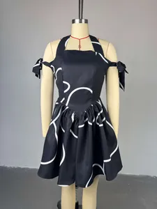 Detail view of a black halter neck dress with white circle prints and bow shoulder straps.