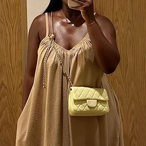 Detalle de vestido largo beige de tirantes con cuello en V y una textura plisada