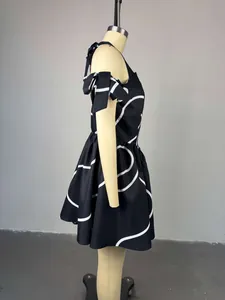 Side view of a black off-shoulder dress with white geometric print and shoulder bows.
