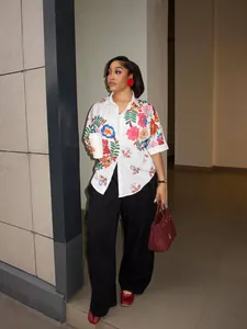 Dettaglio di una camicia bianca a maniche corte con stampe floreali indossata da una modella.