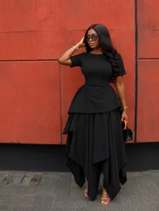 Detailed view of black short-sleeved dress with high waist and irregular layered hem