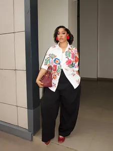 Elegante camicia bianca da donna a maniche corte con ricami e stampe floreali vivaci.