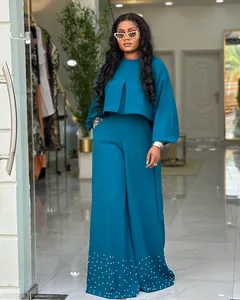 Detail view of teal two-piece set featuring beaded wide-leg pants and puff sleeves