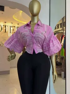 Detailed view of pink eyelet cropped shirt with puff sleeves and rhinestone embellishments