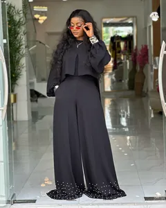 Detailed view of women's black lantern sleeve top and pearl embellished wide leg trousers