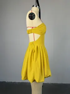 Side view detail of a yellow backless halter mini dress featuring a pleated bubble hem