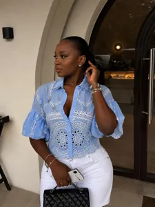 Detailed view of a light blue eyelet shirt with rhinestones and lantern sleeves.