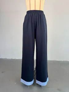 High-waisted wide-leg trousers featuring a unique striped hem detail on a mannequin