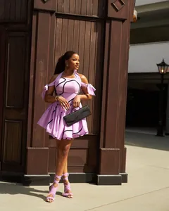 Model wearing a purple halter-neck printed pleated dress with matching lace-up sandals.