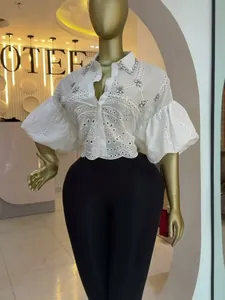 Detailed shot of white eyelet shirt featuring rhinestone accents and voluminous lantern sleeves.